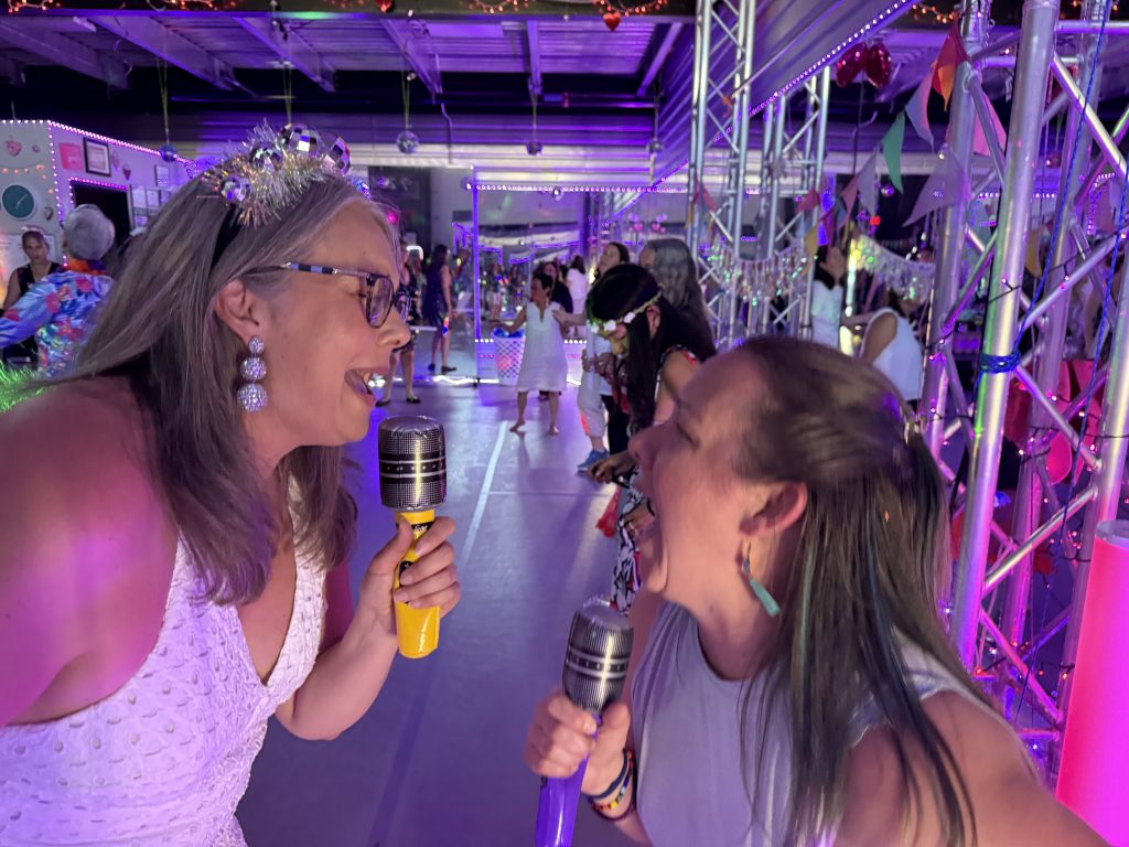 Jennifer and friend signing with a fake microphone
